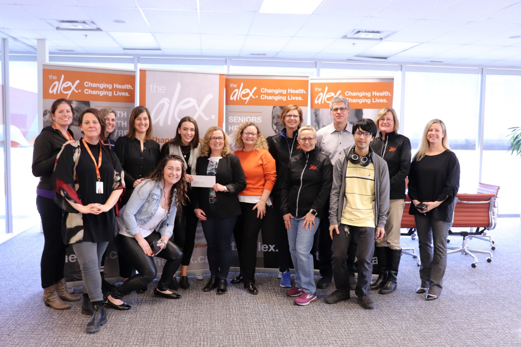 Group of Alex staff and donors smiling for a photo during a check presentation