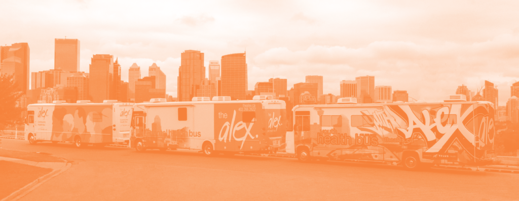Landscape image of The Alex's mobile health bus fleet, including the Community Health Bus, the Dental Health Bus, and the Youth Health Bus. The downtown skyline is in the background. 