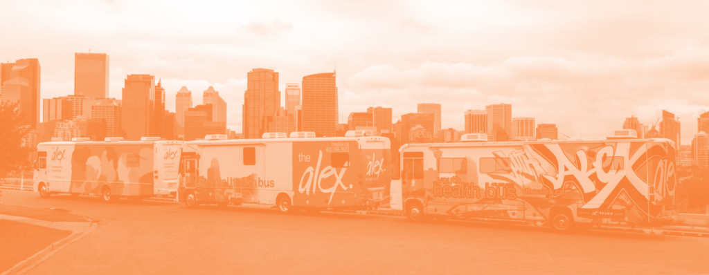 Landscape image of The Alex's mobile health bus fleet, including the Community Health Bus, the Dental Health Bus, and the Youth Health Bus. The downtown skyline is in the background.